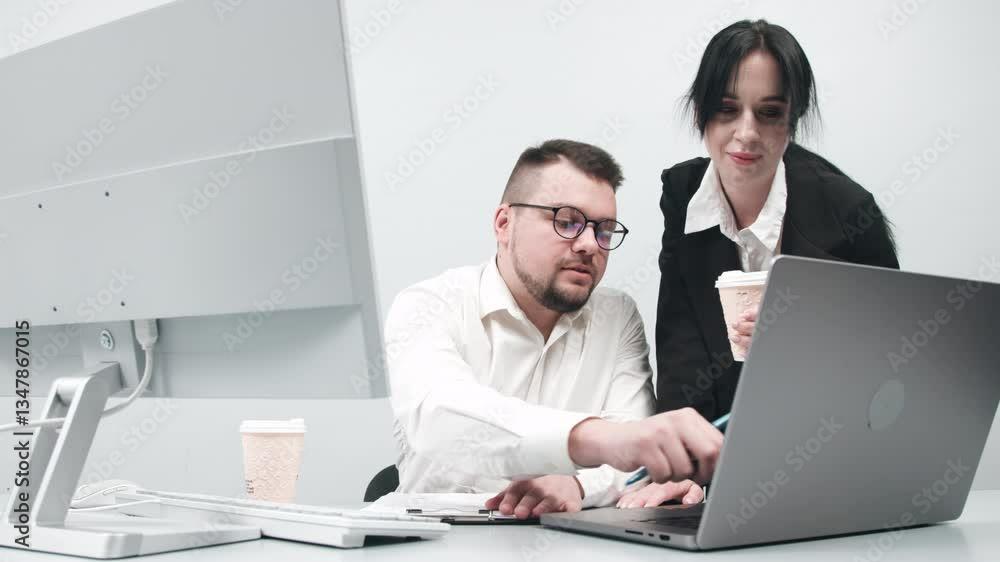 Two business analysts discussing data management with coffee cups next to a laptop. Concept finding solutions, consulting, and client support through online technologies. Two business analysts discussing data management with coffee cups next to a laptop. Concept finding solutions, consulting, and client support through online technologies.