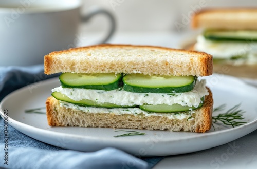 Wallpaper Mural Fresh cucumber sandwich with creamy filling on a white plate, garnished with herbs and a delicate cup of tea in the background, light and inviting setting Torontodigital.ca