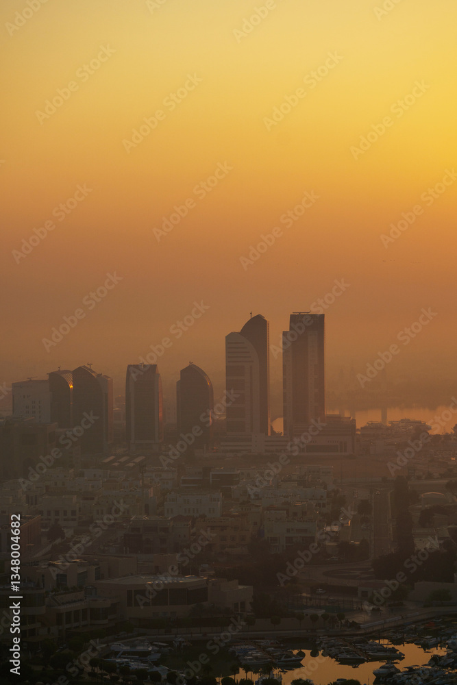 Aerial view of Abu Dhabi in the morning light, as the rising sun casts a golden glow over the city's modern skyline. Aerial view of Abu Dhabi in the morning light, as the rising sun casts a golden glow over the city's modern skyline.