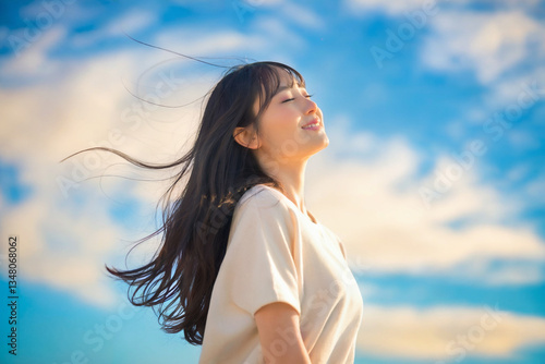 青空の下長い髪が風になびく日本人女性 Generative AI