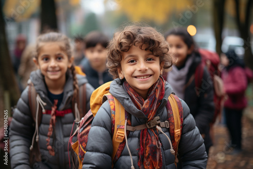  A group of energetic children, carrying colorful backpacks, assembled eagerly in the vibrant park adjacent to their educational institution