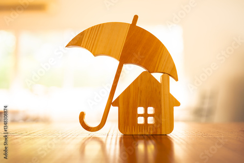 Obraz na płótnie Model of umbrella with house on wooden table concept of the system of insurance savings and Housing insurance against impending loss and fire, building fire insurance concepts