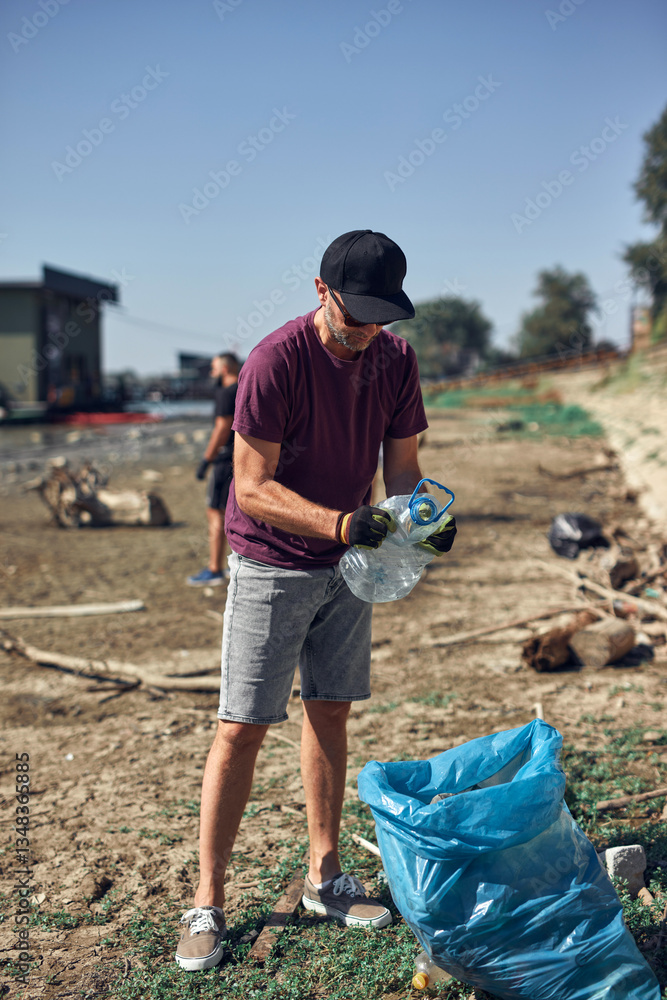 Environmental activist cleaning river shore from piled up trash.