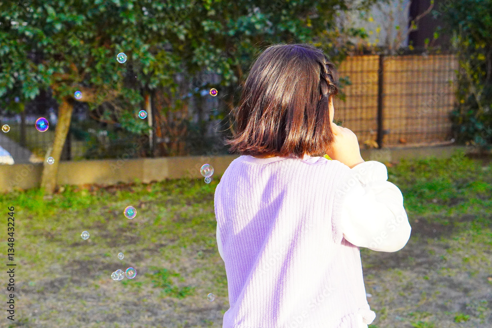 Naklejka premium 春休みの公園で小学生の女の子がシャボン玉遊び