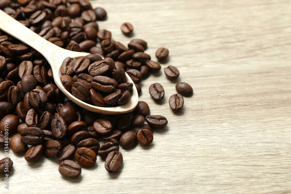 Fototapeta premium Coffee beans in a spoon on wooden background