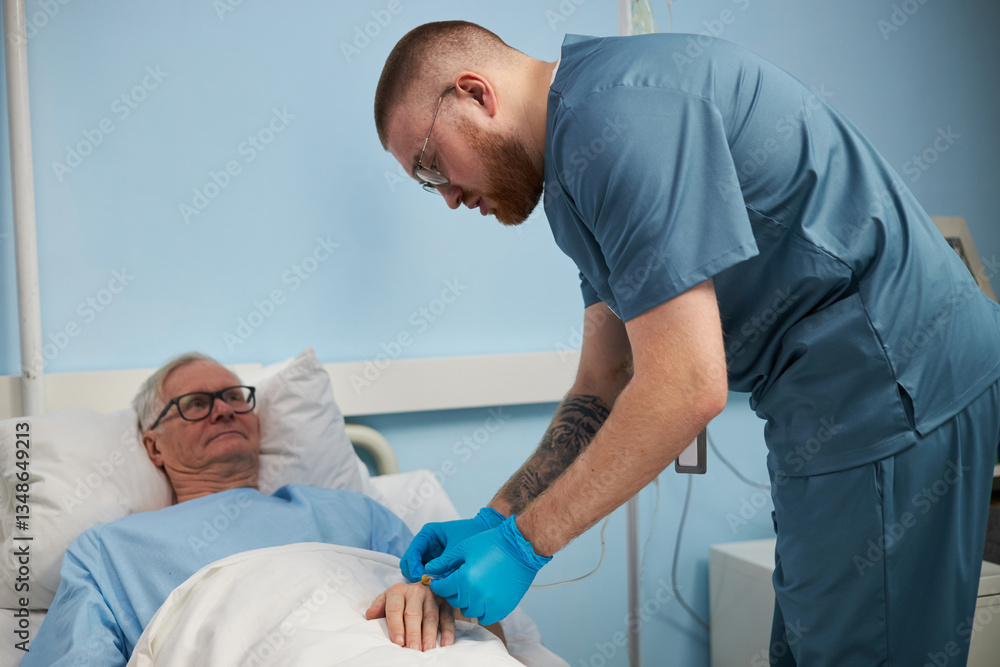 Obraz premium Medical professional wearing blue scrubs checking vital signs of senior patient in hospital room. Patient lying in bed with a calm expression
