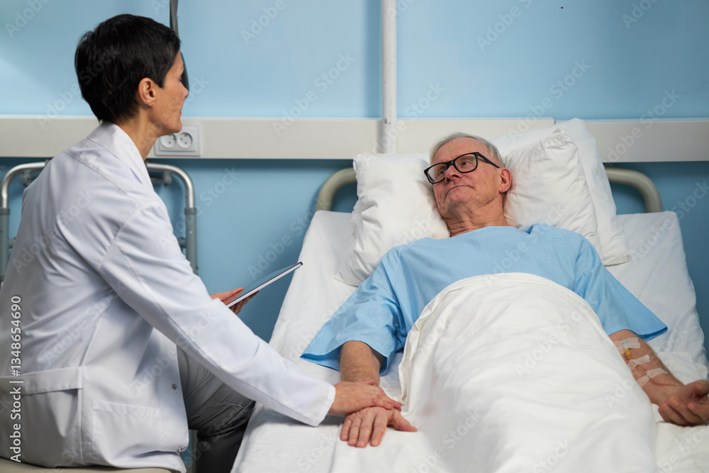 Obraz premium Medical professional holding elderly patient's hand while sitting beside hospital bed, showing empathy and support during difficult time for patient
