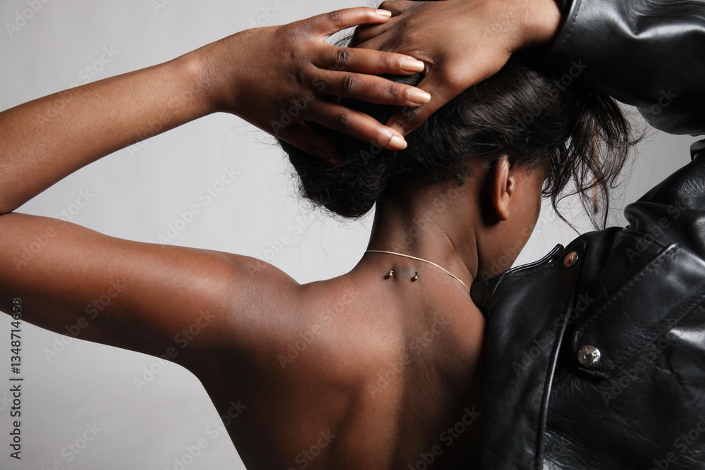 Naklejka premium Back view portrait of young African American woman with glow skin posing over light background.