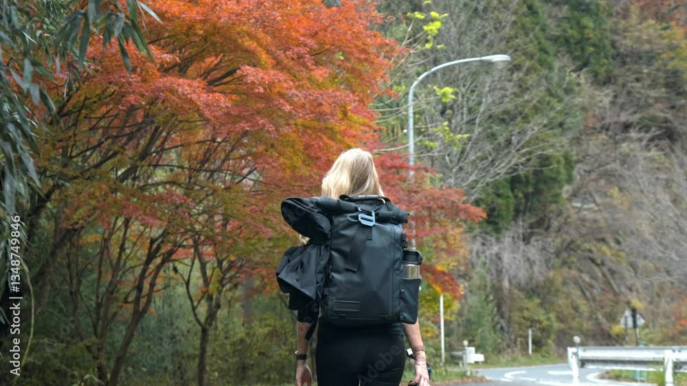 A woman walks through the Nakasendo Trail in Japan, surrounded by vibrant red autumn foliage. The peaceful beauty of the Japanese countryside comes alive during the fall season,. A woman walks through the Nakasendo Trail in Japan, surrounded by vibrant red autumn foliage. The peaceful beauty of the Japanese countryside comes alive during the fall season,.