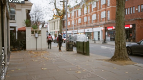 Photography Blurred pedestrians stroll along a leaf-covered london street, capturing a defocused view of an autumn day in chelsea with urban scenery and bokeh background