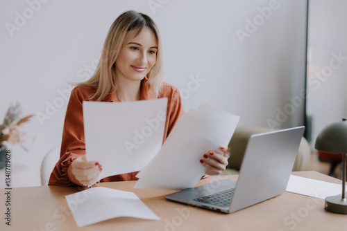 Woman reviewing documents at a desk with a laptop in a calm workspace during daytime