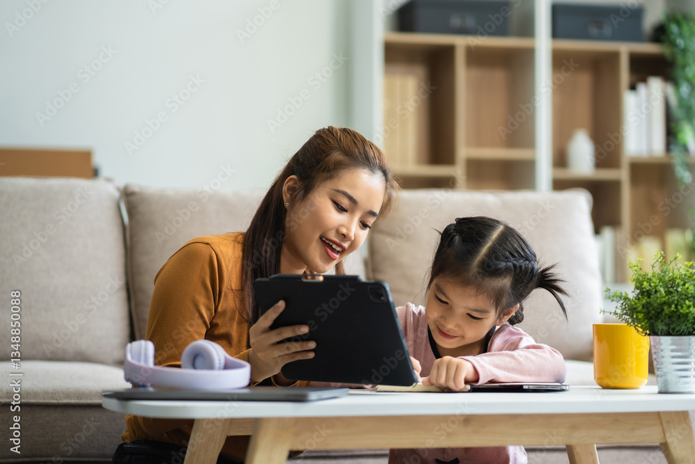 Adorable attentive Little girl writing in notebook and using laptop while doing homework. Adorable attentive Little girl writing in notebook and using laptop while doing homework.
