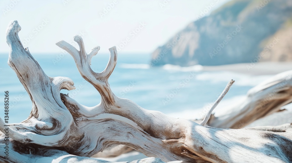 Fototapeta premium Weathered driftwood on sandy beach with ocean and cliffs background