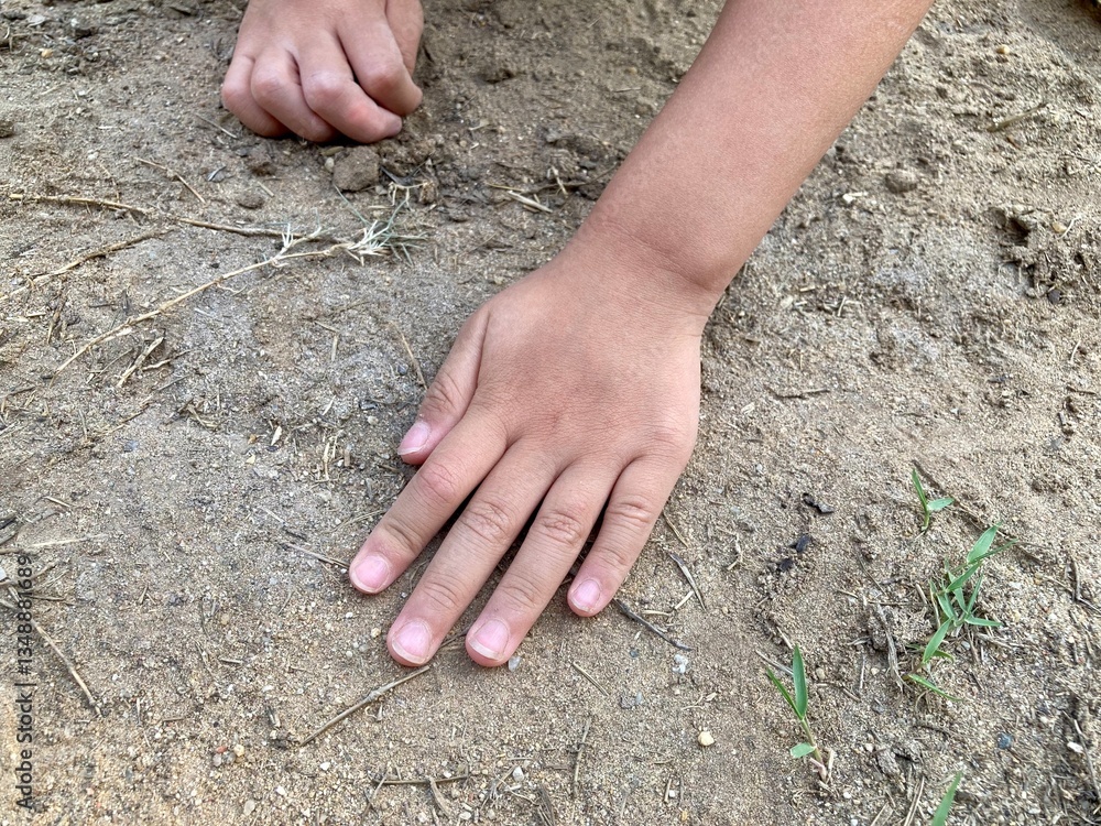 Hands of a preschool boy playing with sand outdoors. Concept of promoting learning, play, child development.
