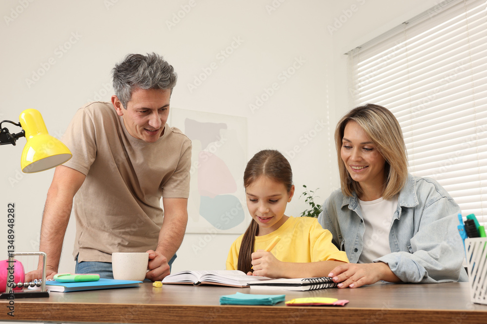Smiling parents helping their daughter with homework at table indoors Smiling parents helping their daughter with homework at table indoors