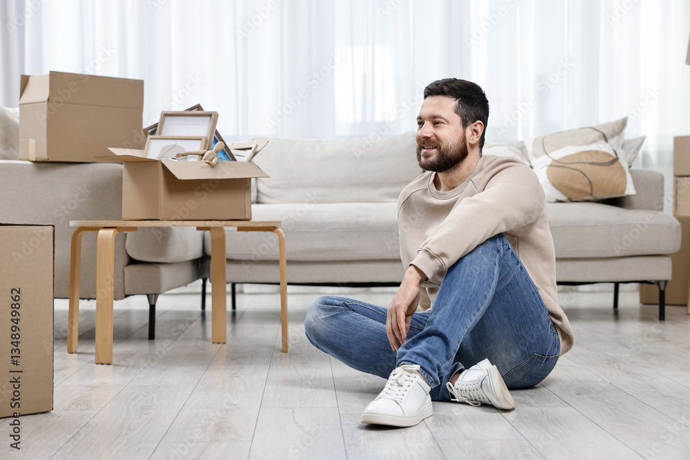 Moving day. Man resting on floor and cardboard boxes in his new home Moving day. Man resting on floor and cardboard boxes in his new home