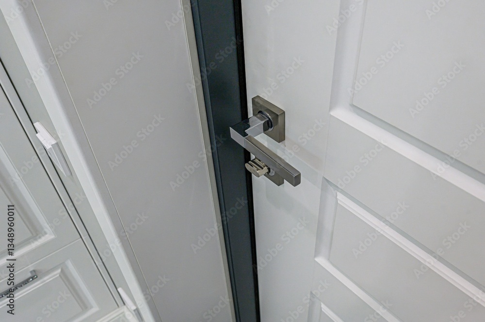 Close-up shot of a modern white door with a sleek, metallic handle. The door features a panel design. Close-up shot of a modern white door with a sleek, metallic handle. The door features a panel design.