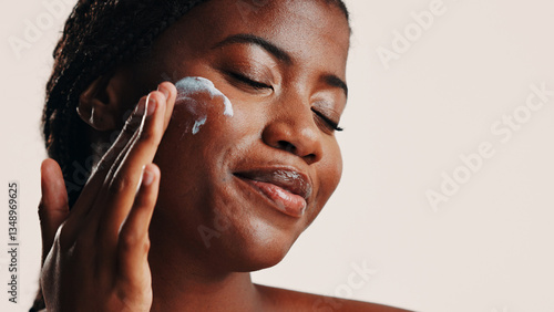 Tableau sur toile Happy, black woman and lotion on face in studio for facial hydration, treatment and sunscreen protection