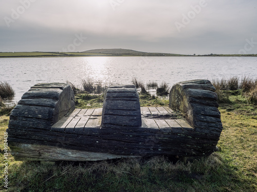A rustic wooden bench by the side of a lake in Cornwall