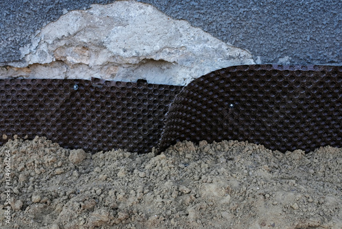 Waterproofing of foundation walls, plastic backingю House foundation waterproofing. Installation of a dimpled waterproofing membrane on the exterior brick house basement wall.