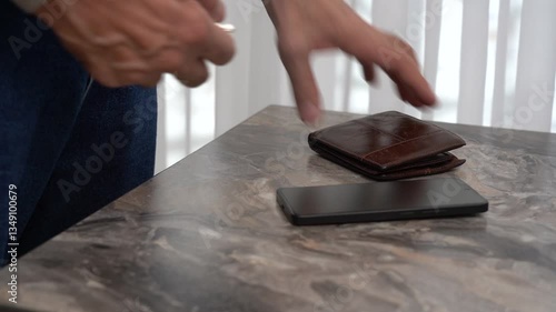 The older man's hands picked up pocket essentials from the table: keys, wallet, phone.