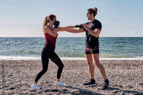 Personal trainer coaching woman boxing on the beach