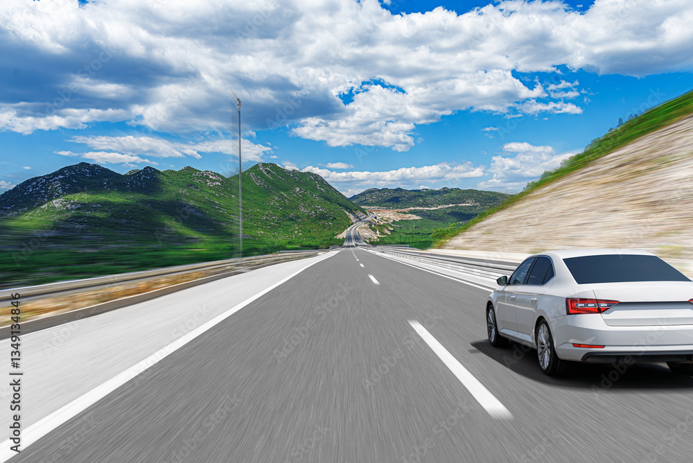 A white sedan speeds along a smooth highway surrounded by lush green mountains under a bright blue sky, capturing the thrill of an open-road journey.