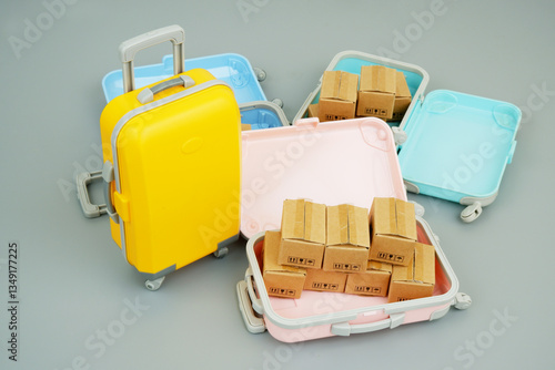 Shipping carton boxes inside suitcases on gray. Shopping and travel concept.