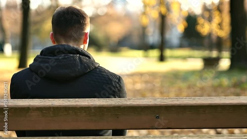 A person sitting alone on a park bench looking dejected