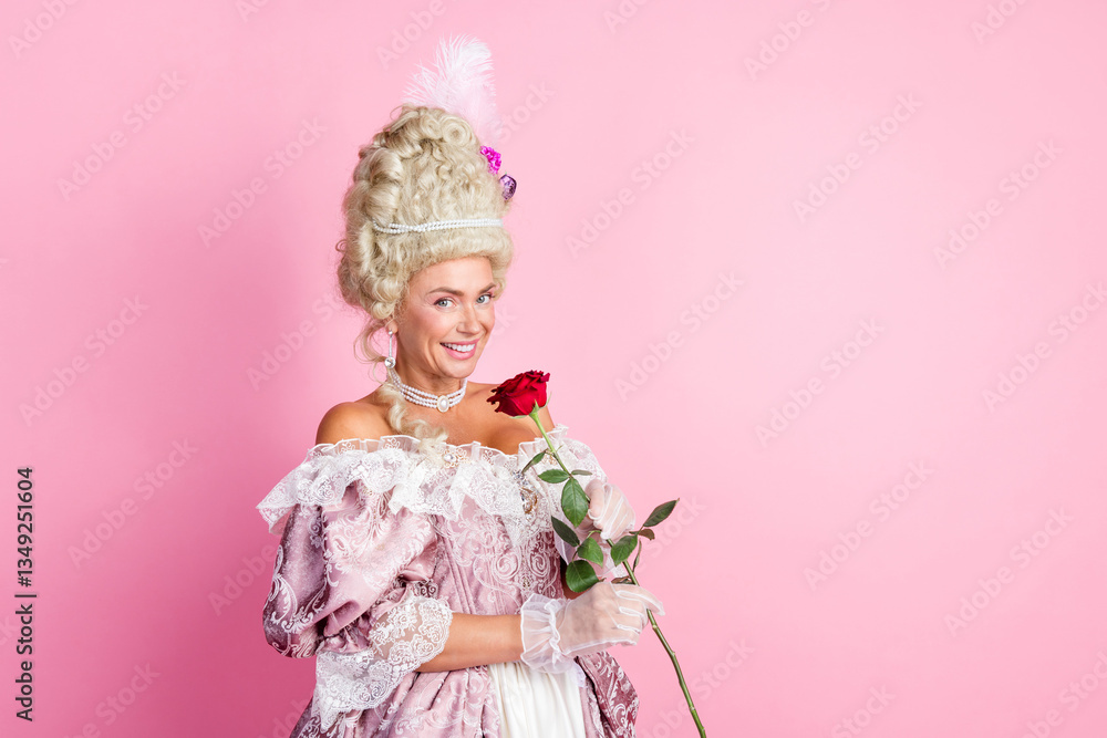 Fototapeta premium Elegant woman in baroque costume holding a rose against a pastel pink background