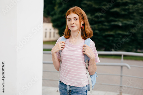Portrait of teen girl in casual wear with backpack near school campus