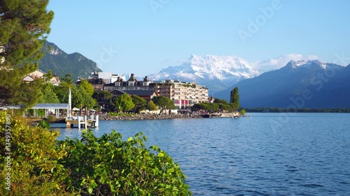 Beautiful summer evening panorama of Lake Geneva with picturesque shores against Alpine mountains in the rays of the setting sun in Montreux, Switzerland. 4K video