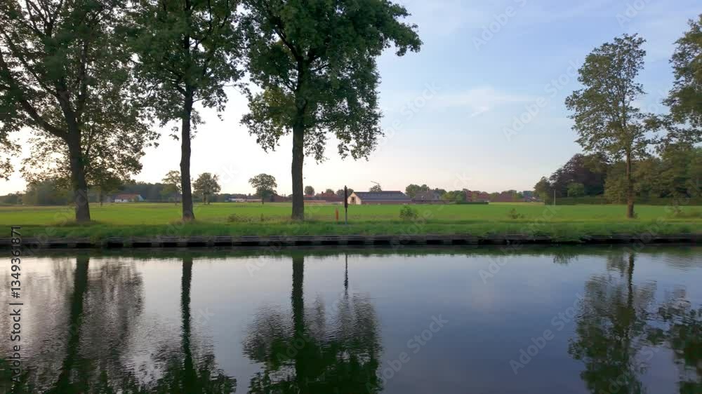 A beautifully tranquil scene featuring a calm waterway that is bordered by lush greenery and thriving trees A beautifully tranquil scene featuring a calm waterway that is bordered by lush greenery and thriving trees