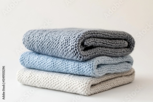 Stack of three knitted blankets in soft grey, light blue, and beige colors.