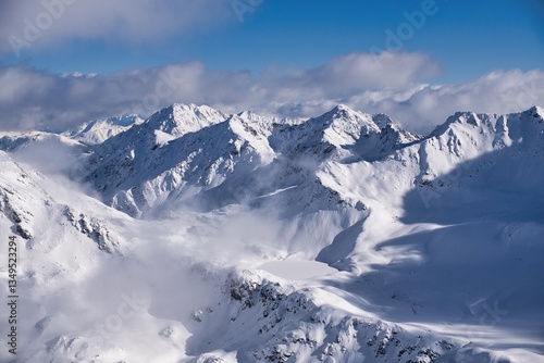 A stunning snowcovered mountain range shines under a clear blue sky, creating a vibrant atmosphere. The breathtaking view showcases stunning snowcapped mountains. dramatic clouds