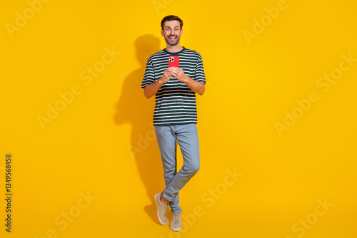 Photography Smiling young man in casual striped t-shirt holding phone with cheerful expressi