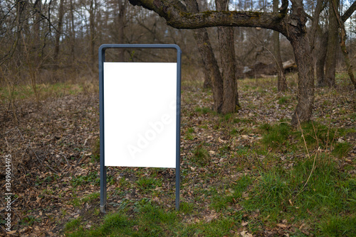 Obraz na płótnie A blank billboard in the forest, standing amidst trees and nature. The empty signboard provides a space for future advertisements, blending with the natural surroundings of the park or woods. w salonie