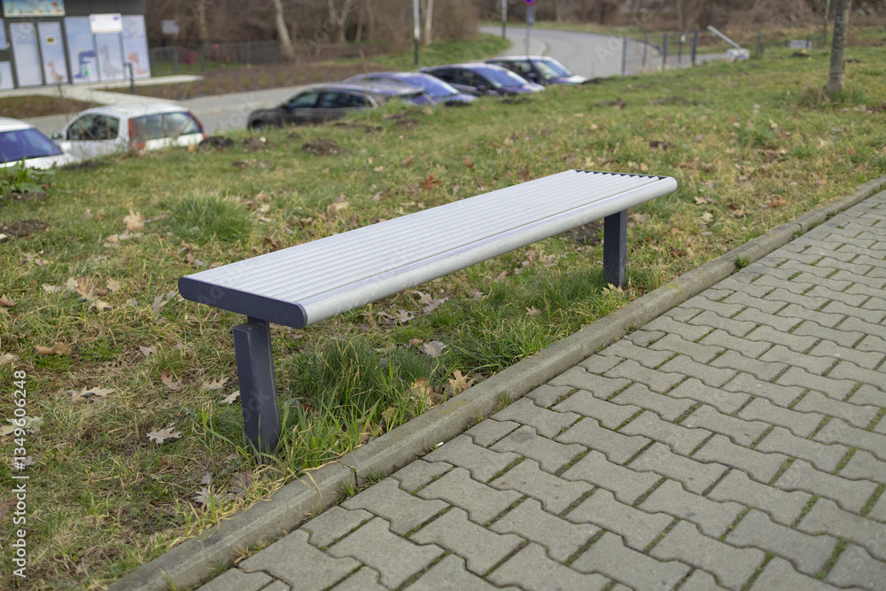 A peaceful park scene featuring a wooden bench along a walking path. The bench provides a place to relax while enjoying the view of the surrounding trees and greenery in a public park