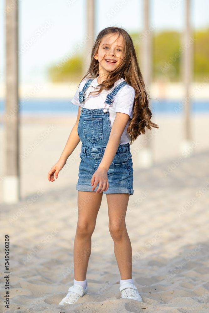 Happy little girl playing and has fun on a white sandy beach near the ocean in summer. Children's holidays. Earth Day. Children's Day. Vacation concept. Space for text Happy little girl playing and has fun on a white sandy beach near the ocean in summer. Children's holidays. Earth Day. Children's Day. Vacation concept. Space for text