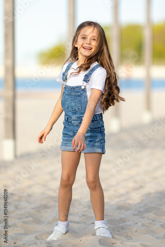Happy little girl playing and has fun on a white sandy beach near the ocean in summer. Children's holidays. Earth Day. Children's Day. Vacation concept. Space for text