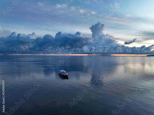 Fotografija An exquisite sunrise illuminates a ship floating in the calm seas surrounding the Togian Island of Central Sulawesi, Indonesia
