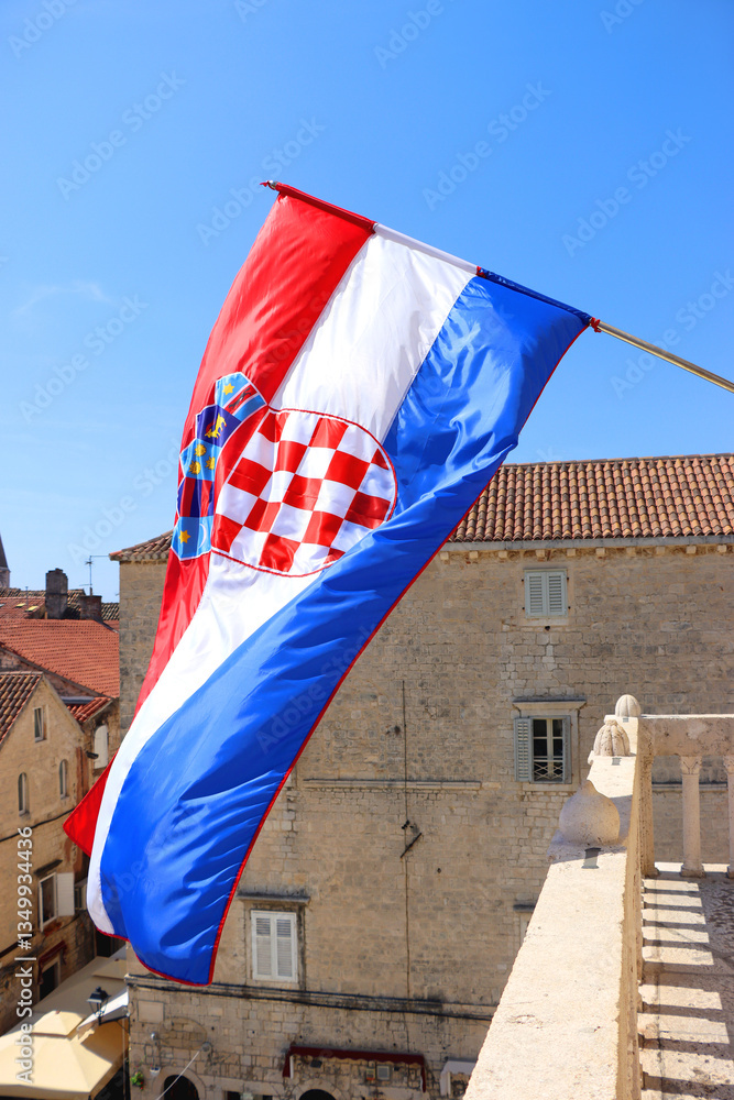 Croatian flag blowing in the wind on the bell tower of The Cathedral of St. Lawrence, landmark in Trogir, Croatia.