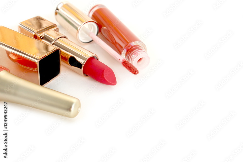 Obraz premium Orange nail polish, lipstick and lip gloss lie on white background with space for text.