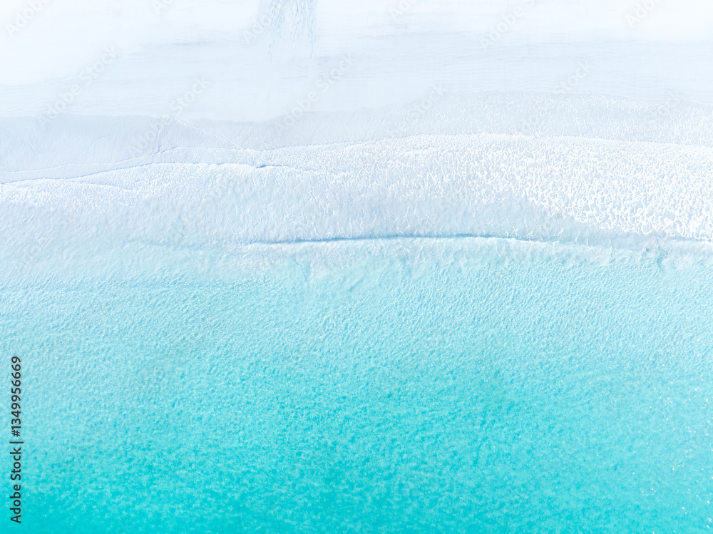Drone view of white sand beach and azure sea. Water on the sea coast. Summer vacation and holiday. Transparent sea water and waves. Photography for background, postcards, wallpapers.