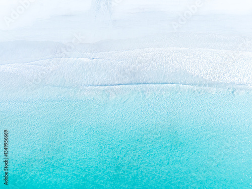 Obraz na płótnie Drone view of white sand beach and azure sea. Water on the sea coast. Summer vacation and holiday. Transparent sea water and waves. Photography for background, postcards, wallpapers. w salonie