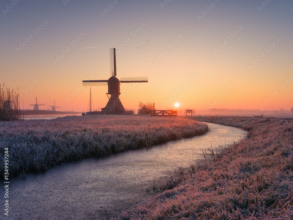 Windmills in the Netherlands during sunrise. Foggy morning and sunshine. Dutch canals. Natural landscape. Photo for background, wallpaper, postcards.