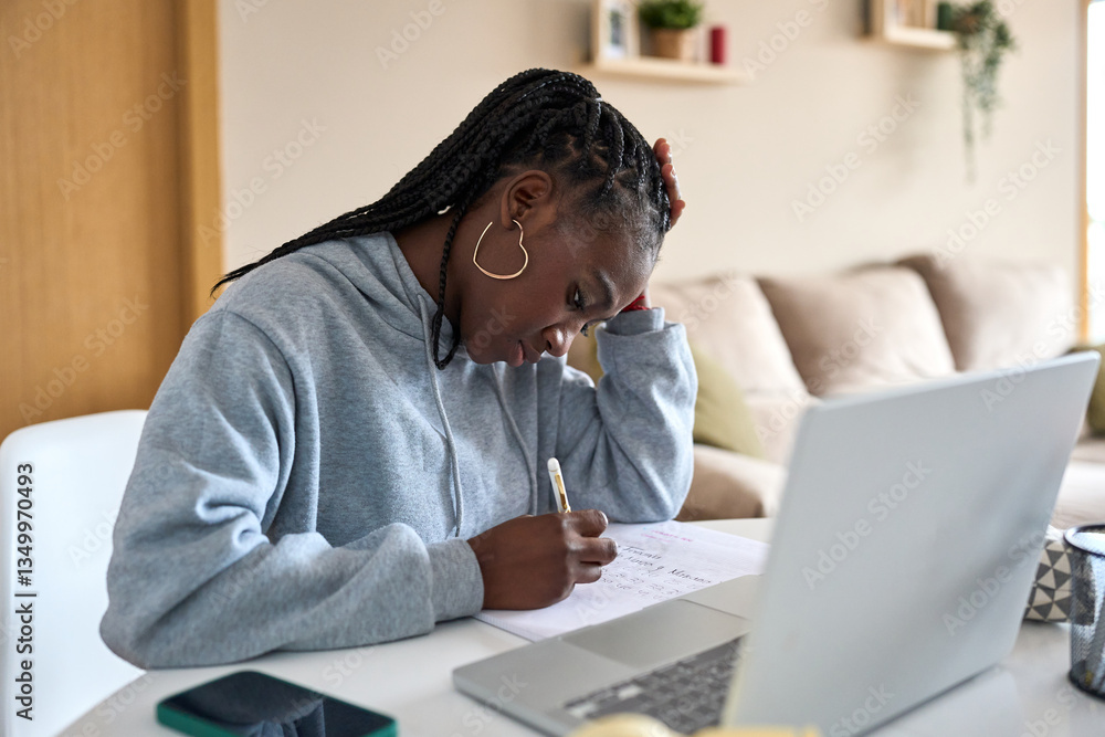 Focused black woman taking notes while studying at home Focused black woman taking notes while studying at home