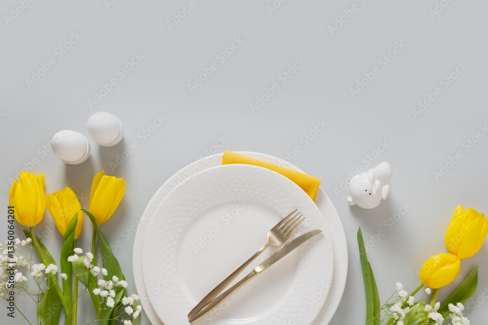 Easter frame with pastel yellow eggs, yellow tulips, gypsophila on gray background. View from above. Happy Easter greeting card.