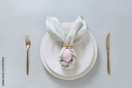 Easter spring table setting with pink egg on gray background. Happy creative Easter decoration. View from above.