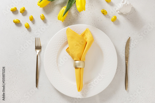 Obraz na płótnie Easter table setting with spring tulips, white plates, bunny, eggs and yellow decoration on white background. Happy Easter celebration. Copy space. View from above. w salonie